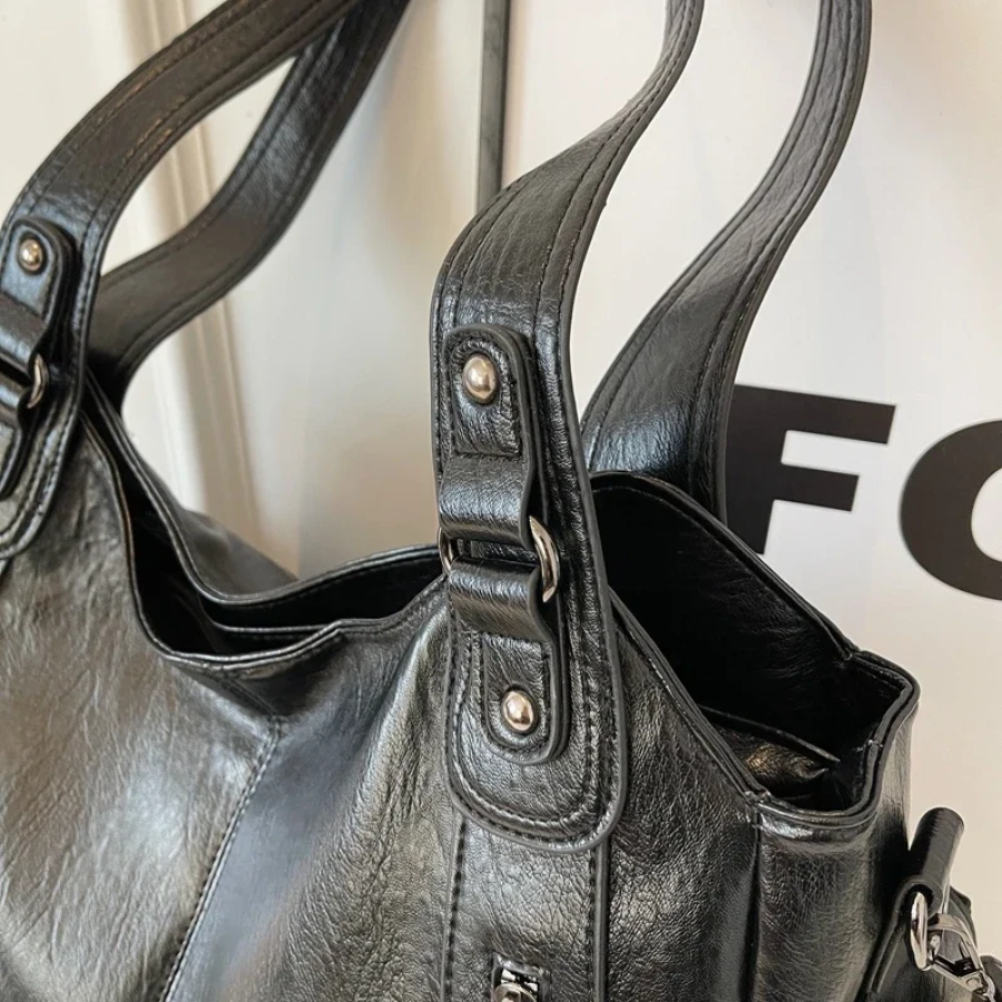 "Amber schoudertas van zacht, vegan leer met elegante metalen details. Ruime, georganiseerde indeling voor dagelijks gebruik.