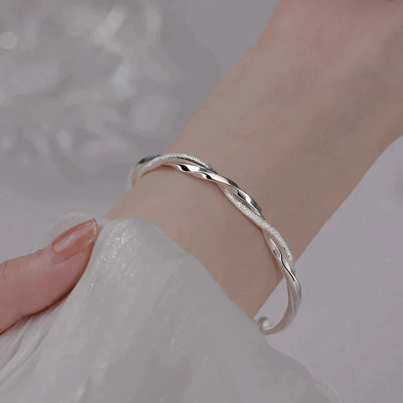 "Elegante gedraaide zilveren armband voor dames, verstelbaar, met glanzende afwerking en modern ontwerp"