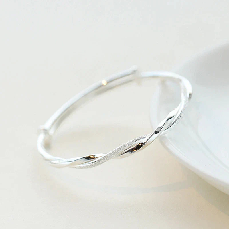 "Elegante gedraaide zilveren armband voor dames, verstelbaar, met glanzende afwerking en modern ontwerp"