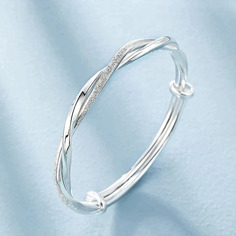 "Elegante gedraaide zilveren armband voor dames, verstelbaar, met glanzende afwerking en modern ontwerp"