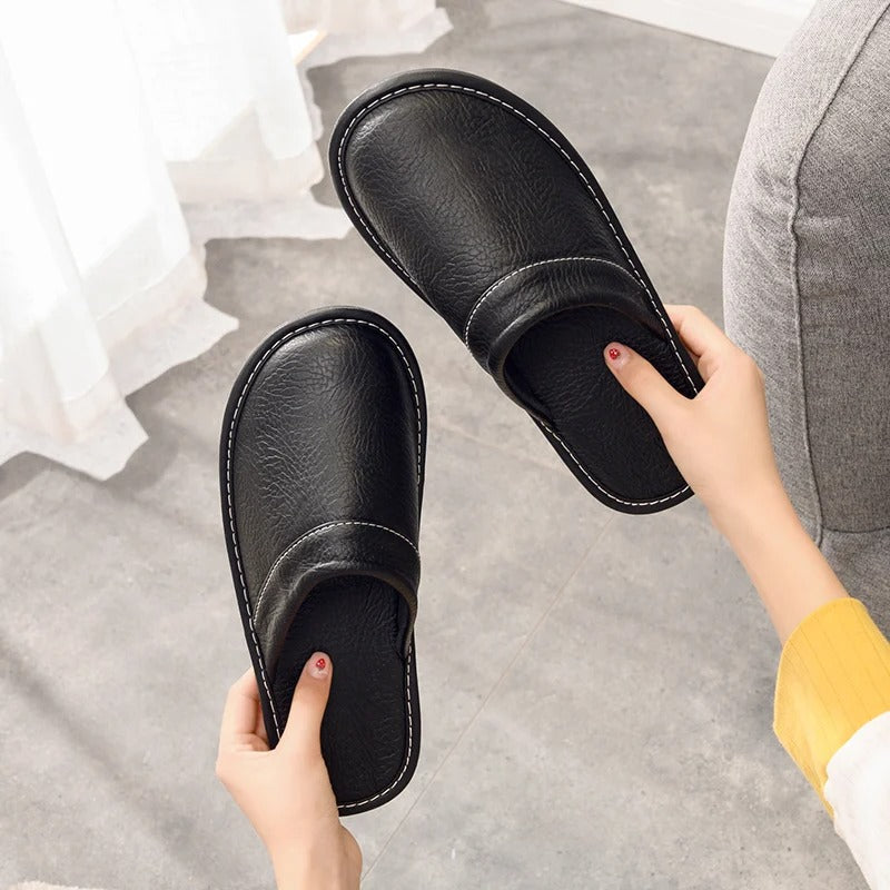 "Heren leren pantoffels met zachte voering, ergonomisch ontwerp en duurzame zool in zwart, getoond op een houten vloer."