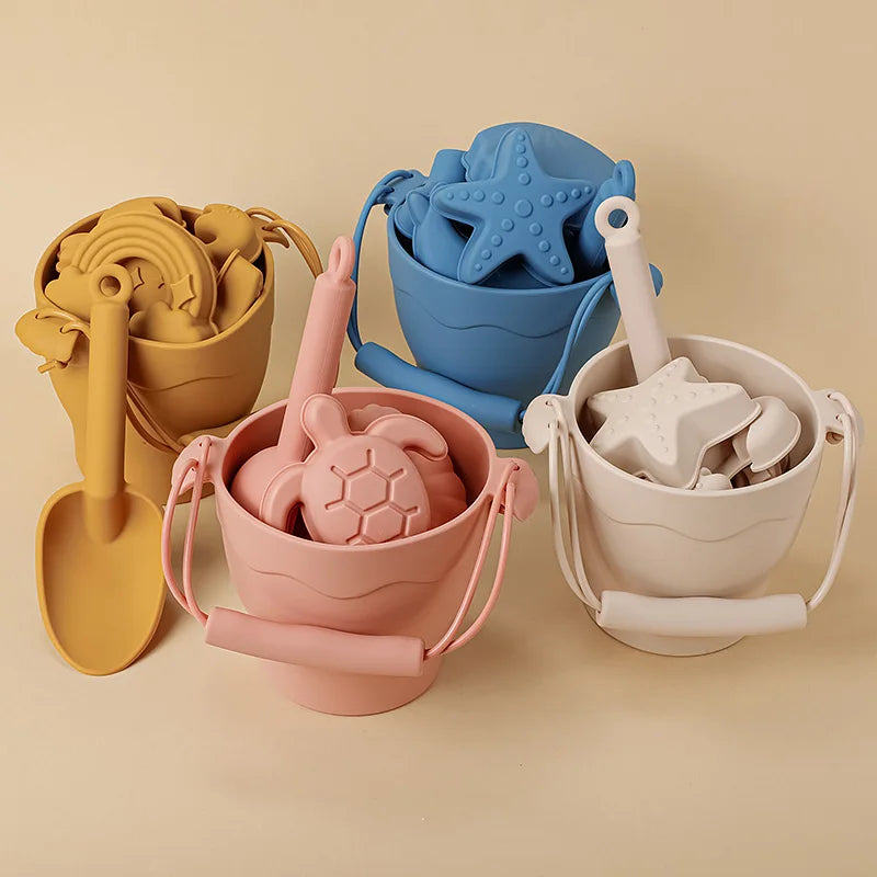 "Vrolijke Silicone Beach Set met emmer en speeltjes in blauwe, gele en groene tinten; veilige, milieuvriendelijke keuze."