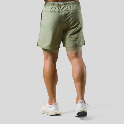"2-in-1 sportbroek voor heren, blauw, met shorts en geïntegreerde zwarte compressielegging voor comfort en ondersteuning."