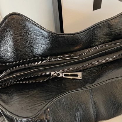 "Amber schoudertas van zacht, vegan leer met elegante metalen details. Ruime, georganiseerde indeling voor dagelijks gebruik.