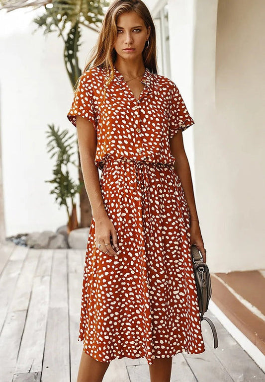 "Elegante Florine midi jurk met strikkoord, luchtige stof, flatterende tailleband en korte mouwen; vrouwelijk ontwerp."