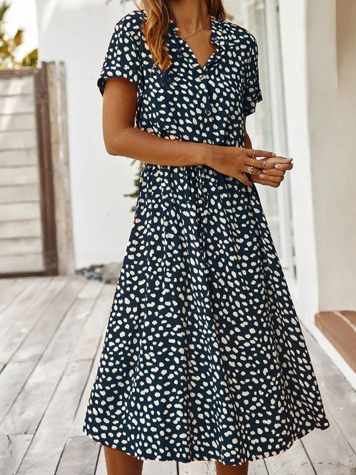 "Elegante Florine midi jurk met strikkoord, luchtige stof, flatterende tailleband en korte mouwen; vrouwelijk ontwerp."