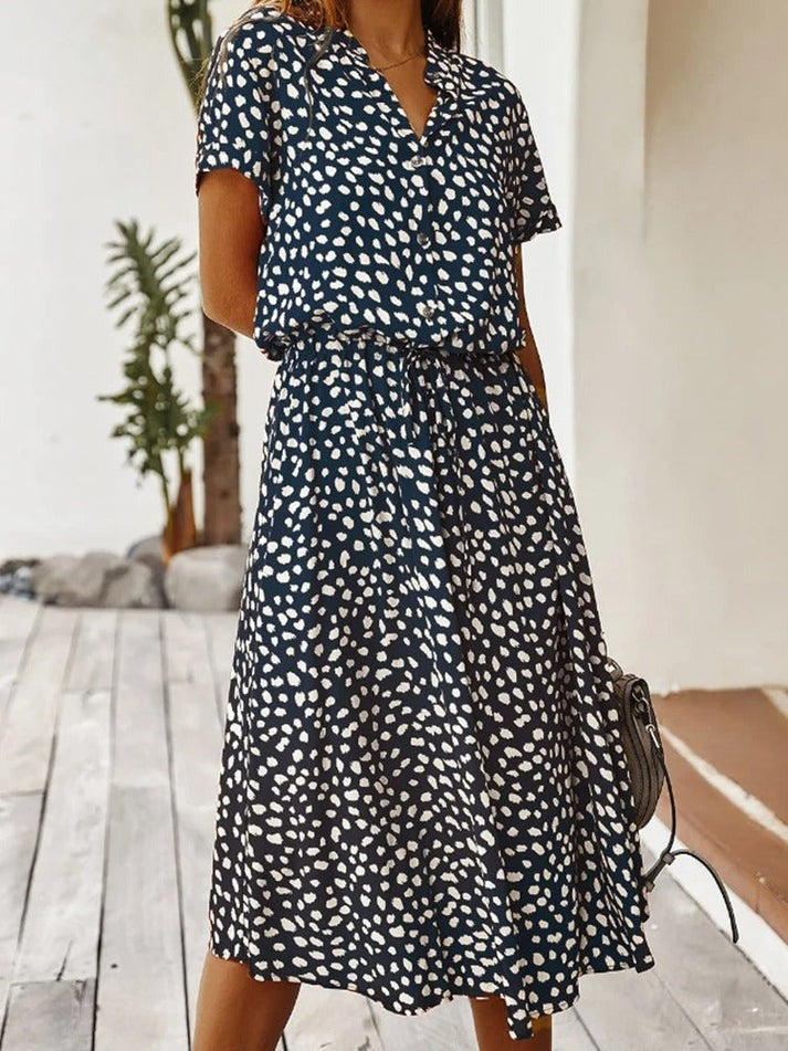 "Elegante Florine midi jurk met strikkoord, luchtige stof, flatterende tailleband en korte mouwen; vrouwelijk ontwerp."