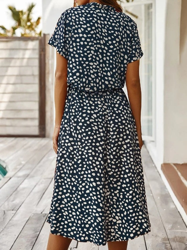 "Elegante Florine midi jurk met strikkoord, luchtige stof, flatterende tailleband en korte mouwen; vrouwelijk ontwerp."