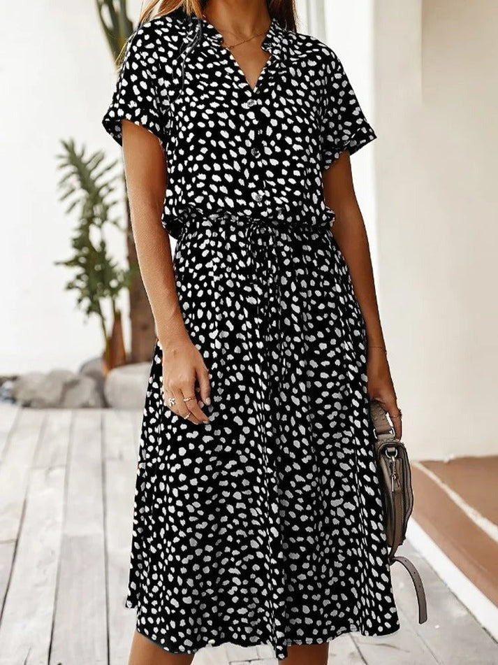"Elegante Florine midi jurk met strikkoord, luchtige stof, flatterende tailleband en korte mouwen; vrouwelijk ontwerp."