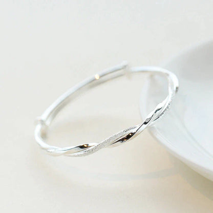 "Elegante gedraaide zilveren armband voor dames, verstelbaar, met glanzende afwerking en modern ontwerp"