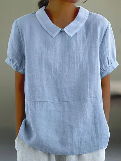 "Lichtblauwe Avaya blouse van katoen met korte mouwen, ronde kraag en subtiele details, ideaal voor zomerse dagen."
