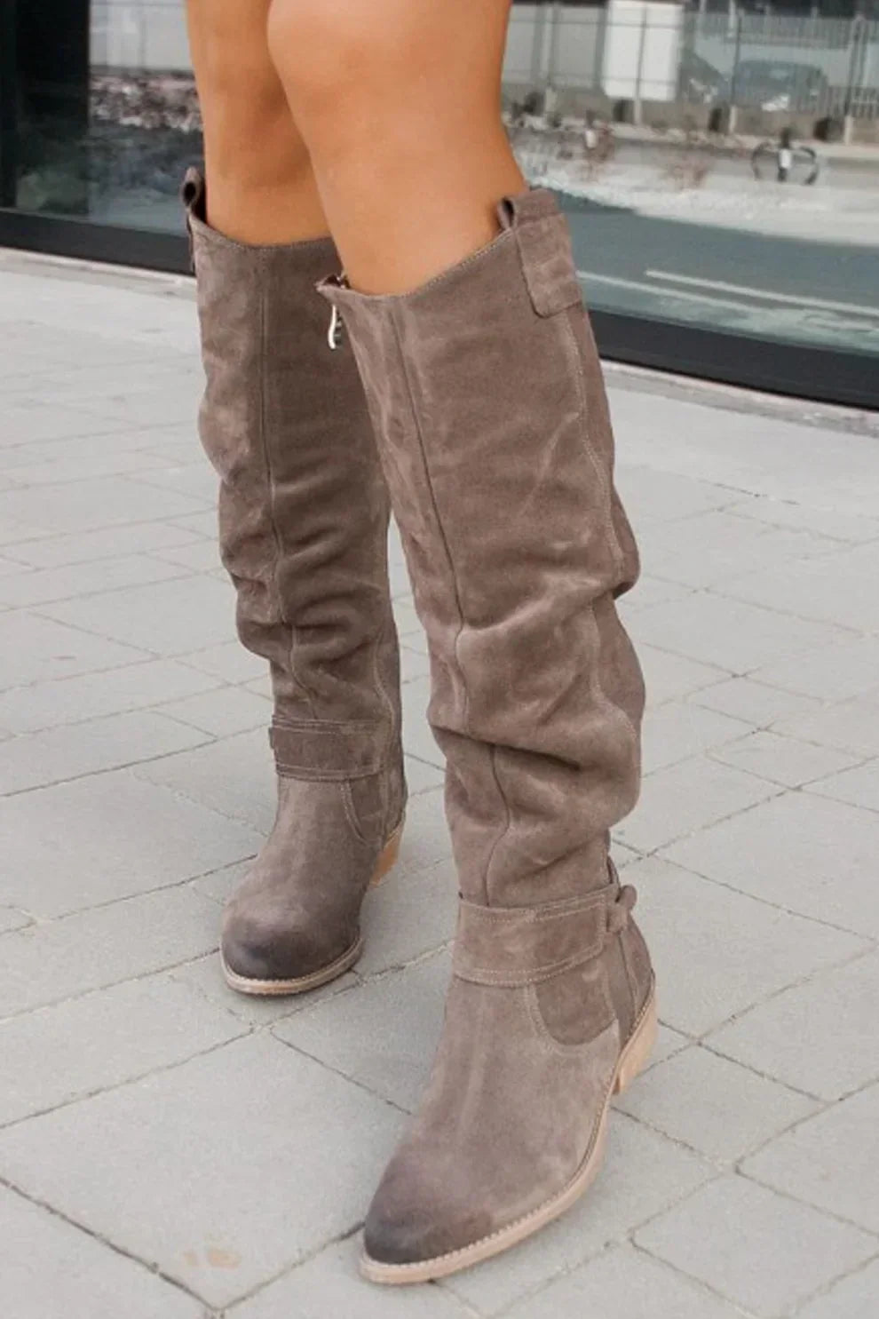 "Nora suède knielaarzen in bruin, elegant design met strikdetail en praktische rits, ideaal voor herfst en winter."